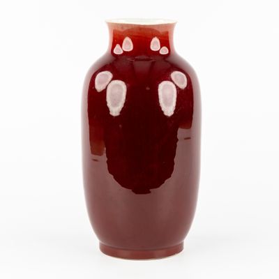 un vase rouge parsemé de taches blanches sur fond blanc