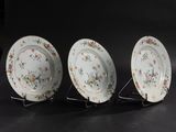 three plates with floral designs on them on a black surface