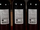 three bottles of wine sitting on top of a table next to a bottle of wine
