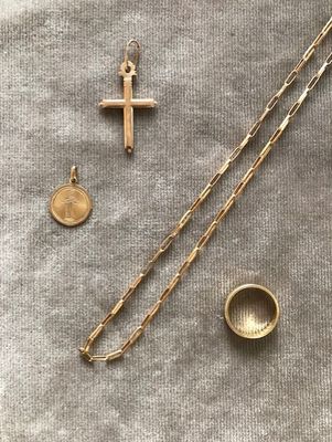 un gros plan sur une croix, une pièce de monnaie et une chaîne posées sur une table