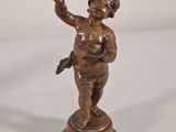 bronze figurine of a boy holding a bird on a pedestal