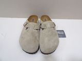 pair of beige sued clogs with buckles on top of a white surface