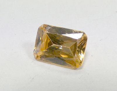 a close up of a yellow diamond on a white surface