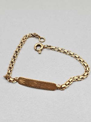 a gold bracelet with an engraved bar on it