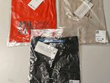 three men ' s t - shirts with tags on them sitting on a table