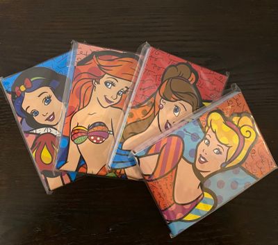 un ensemble de quatre sous-verres à l'effigie des princesses Disney posés sur une table en bois