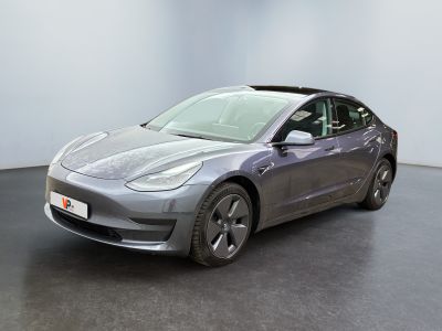 La Tesla Model 3 est garée dans une pièce au sol noir.