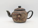 a brown teapot with a floral design on it