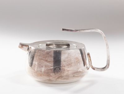 une théière en argent avec une poignée sur une surface blanche