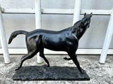 a statue of a horse that is standing in front of a fence