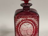 a red glass bottle with a circular design on it