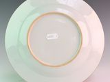 a white plate with a gold rim on a stand