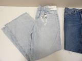 two pairs of jeans sitting on top of a table next to each other