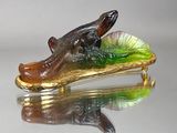 un alligator en verre posé sur une feuille verte