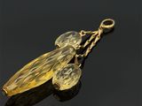 deux feuilles en verre jaune suspendues à une chaîne dorée sur une surface noire