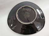 a black plate with a gold rim sitting on a white table