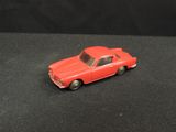 a red toy car that is on a black surface