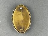 a close up of a gold colored broochle on a gray surface