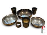 un ensemble de bols et de tasses en métal posés sur une surface blanche