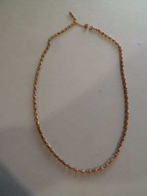 gros plan d'un collier en or sur une surface blanche