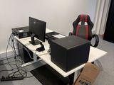 a desk with two computers and a chair in the corner