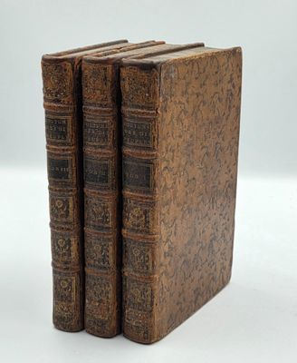 trois vieux livres sont empilés sur une surface blanche
