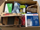 une boîte en carton remplie d'objets divers, posée par terre