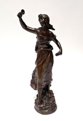 an antique bronze statue of a woman holding a flower