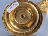 two gold candlesticks on a table with a price tag