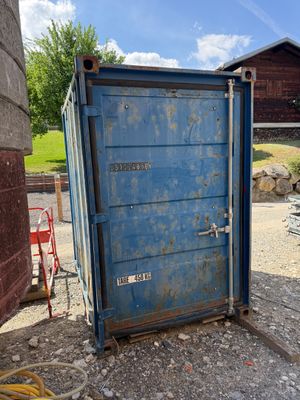 des toilettes portables bleues posées au milieu d'un terrain en terre battue