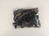 un gros plan d'un sachet de noix noires posé sur une surface blanche