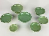six green glass bowls and one bowl are arranged on a white surface