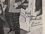 black and white photograph of a man standing in front of a store