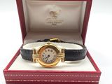 une photo d'une montre en or dans un coffret rouge, avec un bracelet noir