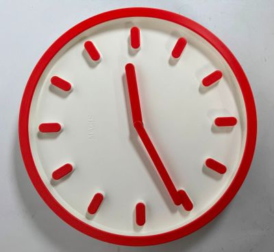 a red and white clock on a white wall