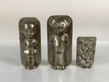 three silver metal figurines of a man and a woman
