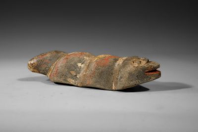 un vieil objet en pierre sur le dos duquel figure une tête de poisson