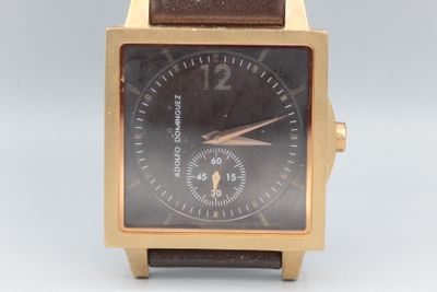 une montre en or avec un cadran noir et un bracelet en cuir marron