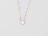 a white diamond flower pendant on a gold chain