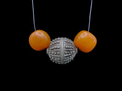 un collier de perles orange orné d'une boule en argent sur fond noir
