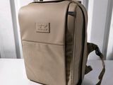 tan leather backpack on a white table with a white background