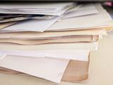 a pile of papers sitting on a desk next to a laptop