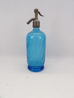 a blue glass bottle with a metal spout on a white surface