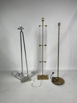 trois lampadaires en métal et en verre posés sur une surface blanche