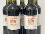quatre bouteilles de vin rouge sont alignées sur une surface blanche