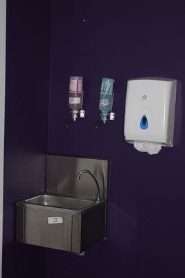 une salle de bains violette équipée d'un lavabo et d'un sèche-mains
