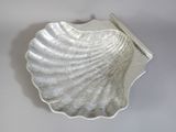 un plat argenté en forme de coquillage posé sur un fond blanc