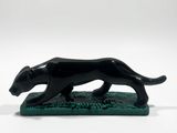 a black dog figurine on a green base on a white background
