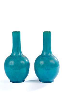 une paire de vases en verre bleu posés sur une surface blanche