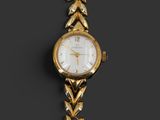 a close up of a gold wrist watch with a chain around it
